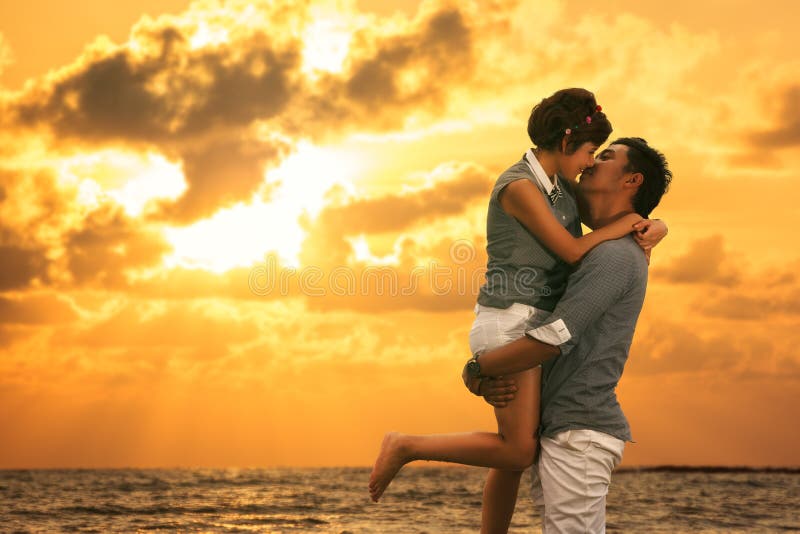 Young asian couple in love staying and kissing on the beach on sunset. Young asian couple in love staying and kissing on the beach on sunset