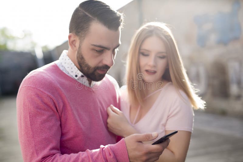 Jeunes couples attrayants dans le style occasionnel une date avec le téléphone portable images libres de droits Jeunes couples attrayants dans le style occasionnel une date avec le téléphone portable images libres de droits