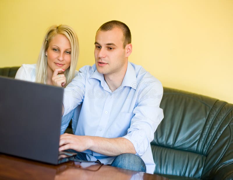 Jeunes couples attrayants utilisant l'ordinateur portatif. image stock Jeunes couples attrayants utilisant l'ordinateur portatif. image stock