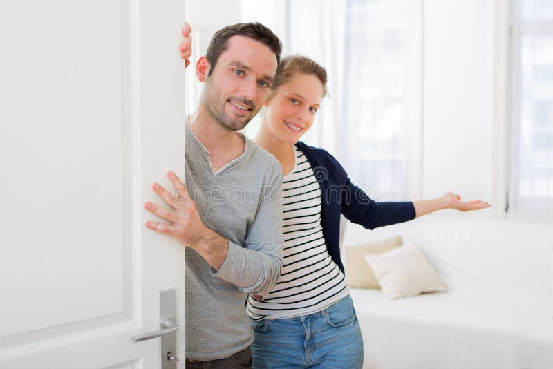 Jeunes couples attrayants vous accueillant dans sa maison photographie stock Jeunes couples attrayants vous accueillant dans sa maison photographie stock