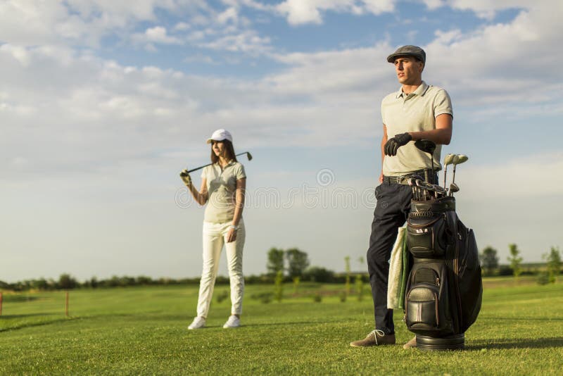 Jeunes couples au chariot de golf photographie stock libre de droits Jeunes couples au chariot de golf photographie stock libre de droits