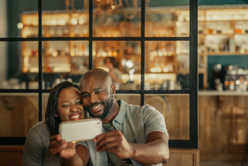 Jeunes couples de sourire prenant des selfies ensemble dans une barre photographie stock Jeunes couples de sourire prenant des selfies ensemble dans une barre photographie stock