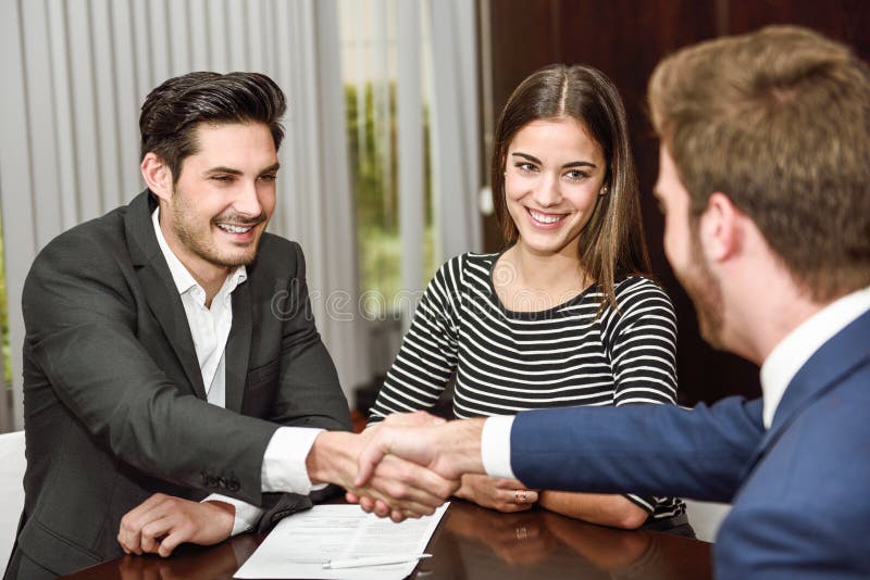 Jeunes couples de sourire serrant la main à un agent d'assurance photo libre de droits