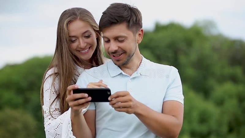 Jeunes couples en utilisant le téléphone portable dans la nature clips vidéos