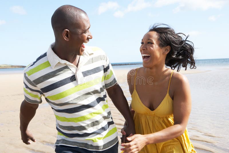 Jeunes couples fonctionnant le long de la fixation H de rivage photo libre de droits Jeunes couples fonctionnant le long de la fixation H de rivage photo libre de droits