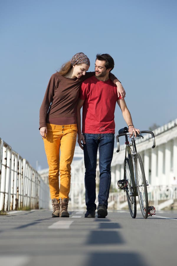 Jeunes couples heureux marchant dehors avec le vélo photos stock Jeunes couples heureux marchant dehors avec le vélo photos stock