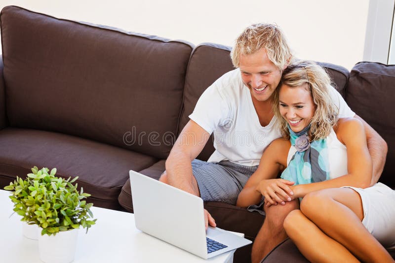 Jeunes couples heureux regardant l'ordinateur portable photo stock Jeunes couples heureux regardant l'ordinateur portable photo stock