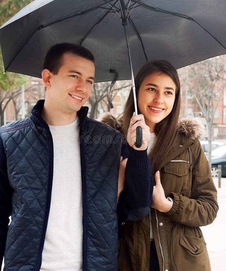 Jeunes couples heureux souriant sous le parapluie photos libres de droits Jeunes couples heureux souriant sous le parapluie photos libres de droits