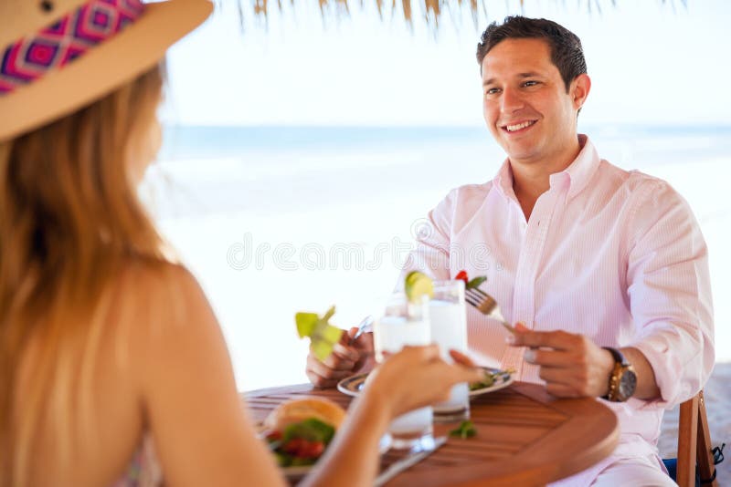 Jeunes couples mangeant le déjeuner à la plage photos stock Jeunes couples mangeant le déjeuner à la plage photos stock