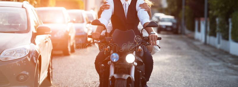 Jeunes couples montant une moto moderne au coucher du soleil images stock Jeunes couples montant une moto moderne au coucher du soleil images stock