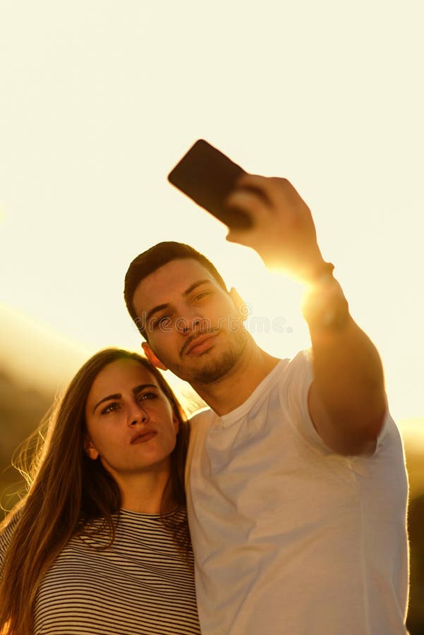 Jeunes couples prenant le selfie avec le smartphone sur le dessus de toit photographie stock Jeunes couples prenant le selfie avec le smartphone sur le dessus de toit photographie stock