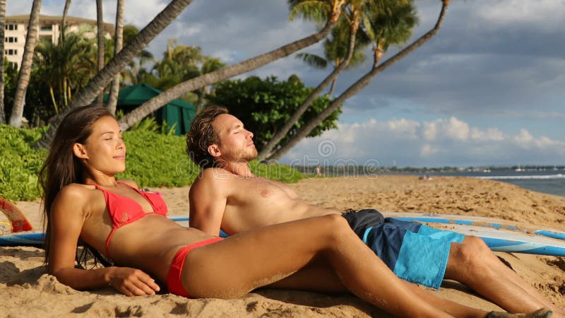 Jeunes couples reposant après avoir surfé sur la plage de Maui, Hawaii banque de vidéos