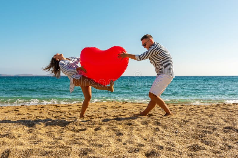 Jeunes couples s'amusant sur la plage avec un grand ballon au coeur Concept d'amour d'été images libres de droits Jeunes couples s'amusant sur la plage avec un grand ballon au coeur Concept d'amour d'été images libres de droits