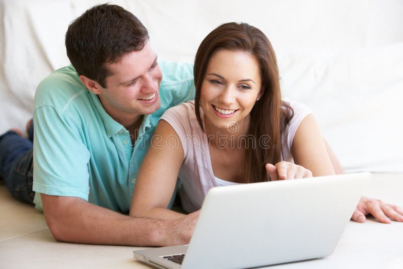 Jeunes couples sur l'ordinateur portable image stock Jeunes couples sur l'ordinateur portable image stock