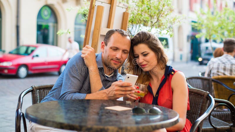 Jeunes couples utilisant des téléphones portables dans un café. images libres de droits Jeunes couples utilisant des téléphones portables dans un café. images libres de droits