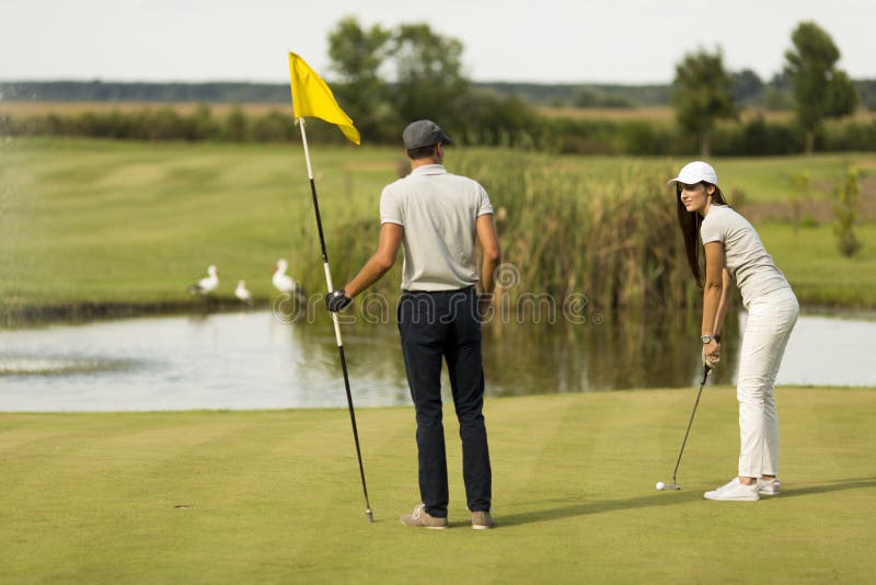 Jeunes couples à la cour de golf image libre de droits Jeunes couples à la cour de golf image libre de droits