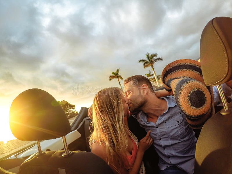 Jeunes couples à la mode ayant un moment tendre dans la voiture convertible pendant leur voyage par la route - baisers romantique photos stock Jeunes couples à la mode ayant un moment tendre dans la voiture convertible pendant leur voyage par la route - baisers romantique photos stock