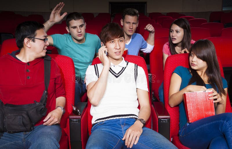 Jeunes hommes parlant au téléphone tout en observant le film photographie stock libre de droits Jeunes hommes parlant au téléphone tout en observant le film photographie stock libre de droits