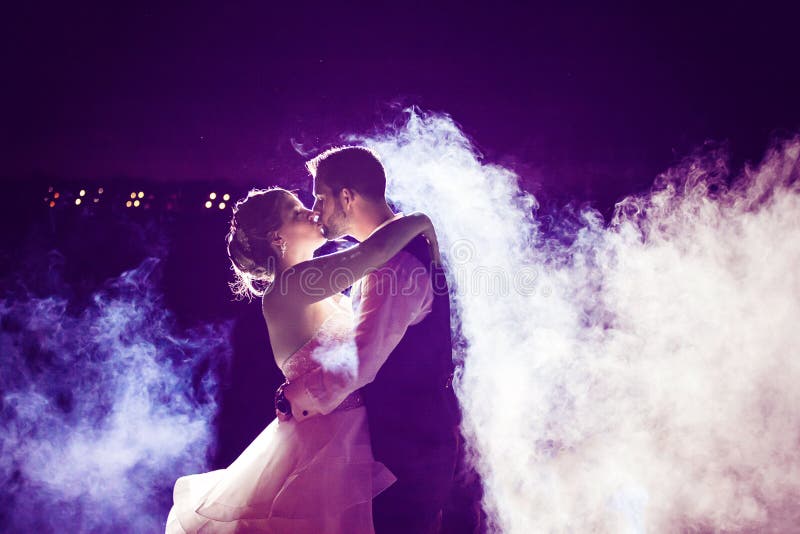 Jeunes mariés embrassant en brouillard avec le ciel nocturne pourpre image stock