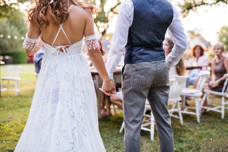 Jeunes mariés méconnaissables avec des invités à la réception de mariage dehors dans l'arrière-cour photos stock Jeunes mariés méconnaissables avec des invités à la réception de mariage dehors dans l'arrière-cour photos stock