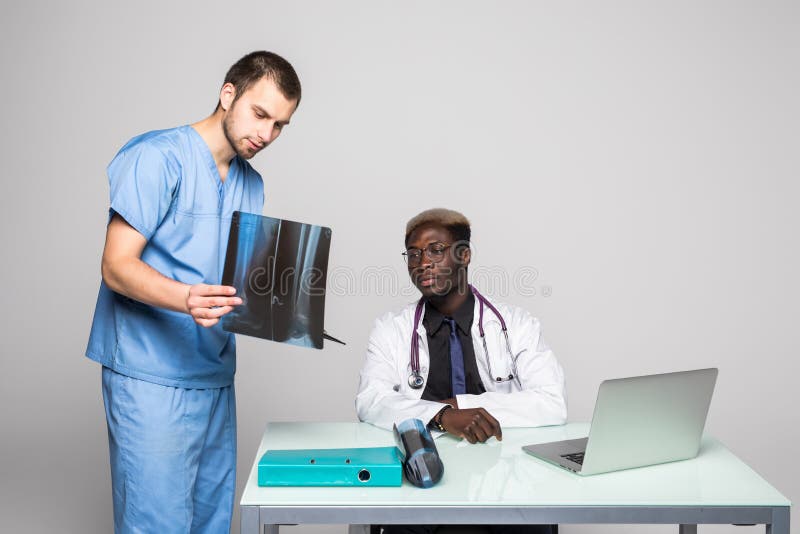 Jeunes médecins discutant le diagnostic dans le bureau lumineux Deux médecins disscusing le rayon X à la table de bureau d'isolem photos stock Jeunes médecins discutant le diagnostic dans le bureau lumineux Deux médecins disscusing le rayon X à la table de bureau d'isolem photos stock
