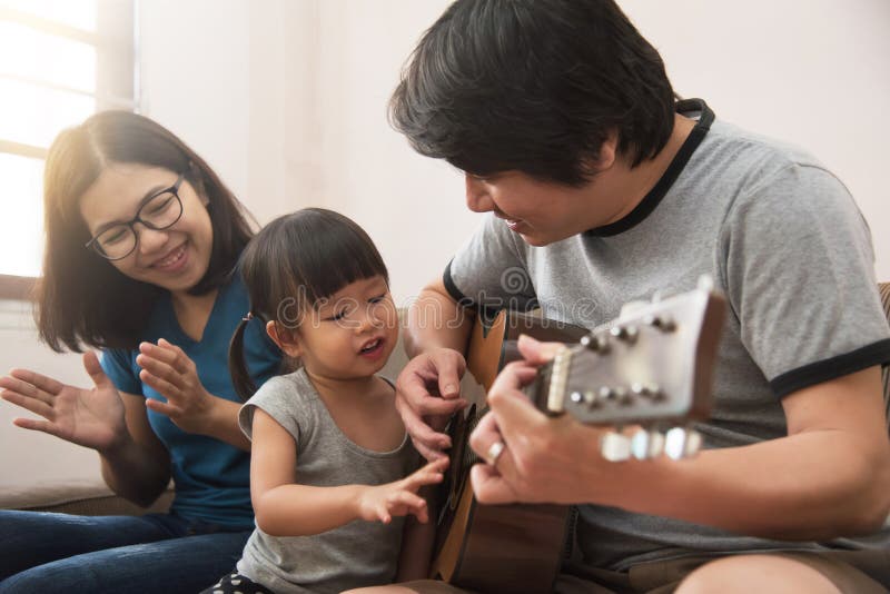 Jeunes père, mère asiatique et fille jouant le toget de guitare photos libres de droits Jeunes père, mère asiatique et fille jouant le toget de guitare photos libres de droits