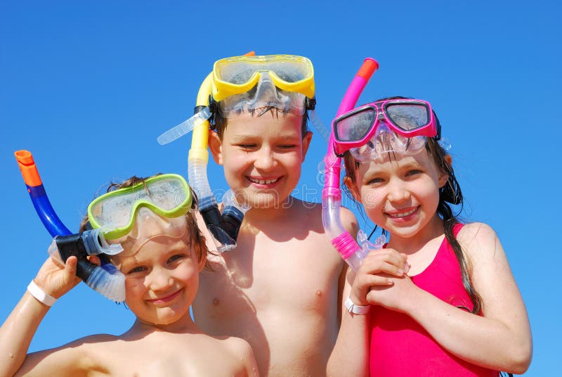 A view of three children ready for a day in the water at the beach with their swimming goggles and snorkels. A view of three children ready for a day in the water at the beach with their swimming goggles and snorkels.