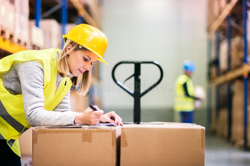 Jeunes travailleurs travaillant dans un entrepôt photographie stock libre de droits Jeunes travailleurs travaillant dans un entrepôt photographie stock libre de droits