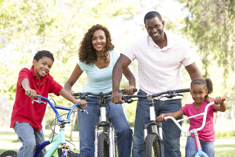 Jeunes vélos d'équitation de famille en stationnement image stock Jeunes vélos d'équitation de famille en stationnement image stock