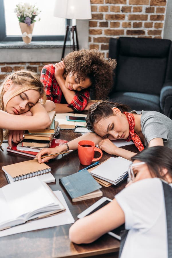 Jeunes étudiants dormant sur la table avec des carnets et des dispositifs numériques images libres de droits