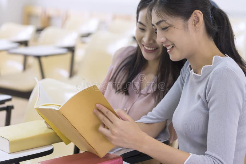 Jeunes étudiants universitaires lisant un livre ensemble dans la classe Educati images libres de droits Jeunes étudiants universitaires lisant un livre ensemble dans la classe Educati images libres de droits