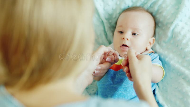 Jeux de maman avec le bébé Un garçon de deux mois sur le lit, femme arrière d'épaule de vue clips vidéos
