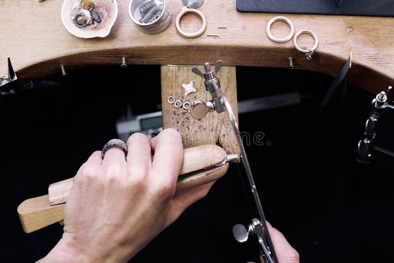 Jeweler at work in jewelery workshop, woman hands making silver thing. tools set.