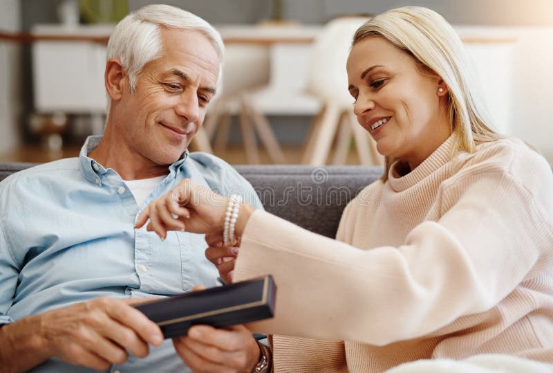 Jewelry, gift and mature couple in home for anniversary, love and romantic gesture in living room. Happy woman, man and stock images