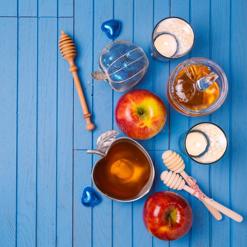 Jewish holiday Rosh Hashana still life with honey, apples and candles on wooden blue table. View from above.