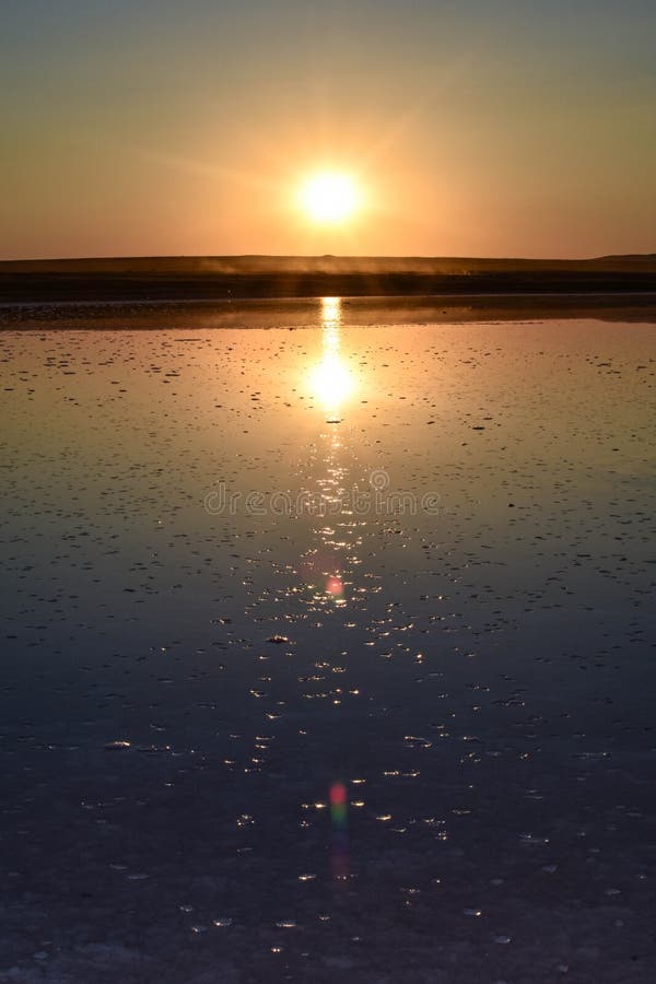 Jezioro słone o zachodzie słońca, słońce o zachodzie słońca odbite w wodzie