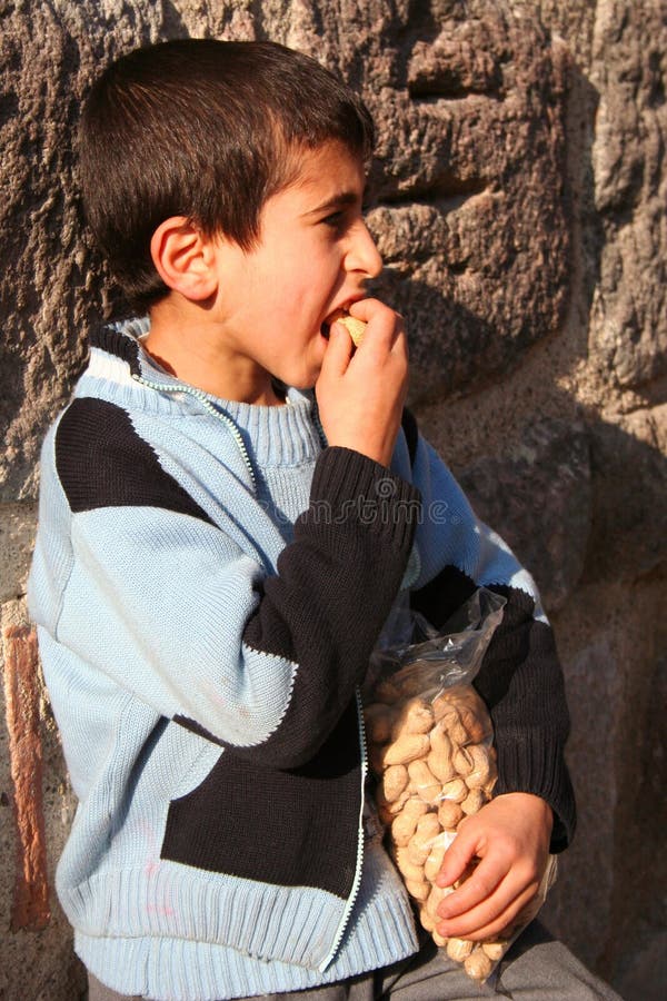 A hungry child eating his peanuts. A hungry child eating his peanuts