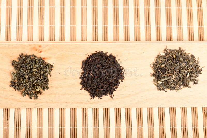 Closeup of three piles with dried leaves tea, of type: jiaogulan, black and green. Closeup of three piles with dried leaves tea, of type: jiaogulan, black and green