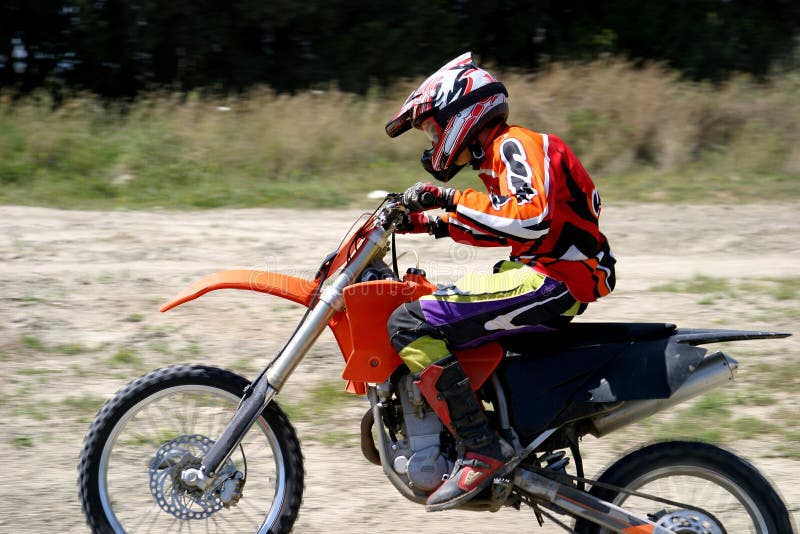 Jinete de la bici de Moto que apresura X con el fondo enmascarado como él acomete más allá en pista de suciedad imagenes de archivo Jinete de la bici de Moto que apresura X con el fondo enmascarado como él acomete más allá en pista de suciedad imagenes de archivo