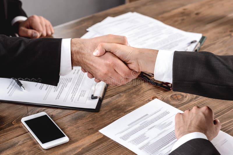 Job Interview. Employer and candidate sitting in office shaking hands deal close-up. Employer and candidate sitting in office having job interview shaking hands stock photography Job Interview. Employer and candidate sitting in office shaking hands deal close-up. Employer and candidate sitting in office having job interview shaking hands stock photography