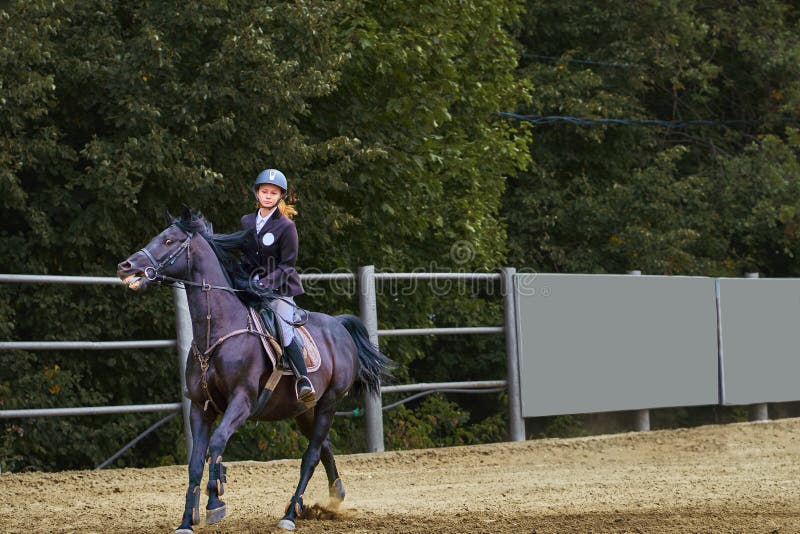 Jockey för ung kvinna i den vita svarta klänningen och svarta kängor arkivbild