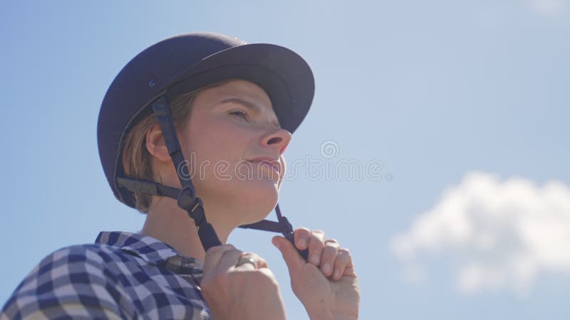 Jockey joven preparado para la competencia de equitación poniendo casco de seguridad