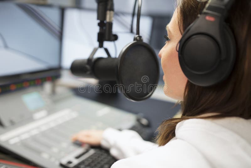 Jockey Wearing Headphones While som använder mikrofonen i radiostudio royaltyfria foton Jockey Wearing Headphones While som använder mikrofonen i radiostudio royaltyfria foton