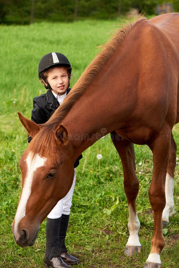 Jockey μικρών κοριτσιών παρευρίσκεται και βουρτσίζοντας το άλογό της στοκ φωτογραφία Jockey μικρών κοριτσιών παρευρίσκεται και βουρτσίζοντας το άλογό της στοκ φωτογραφία