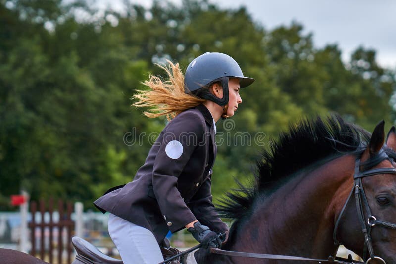 Jockeyn för den unga kvinnan i vitsvartklänningen, tagande särar i rid- konkurrenser arkivfoto