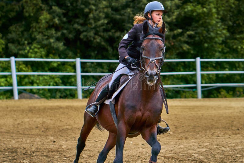 Jockeyn för den unga kvinnan i vitsvartklänningen, tagande särar i rid- konkurrenser royaltyfria foton