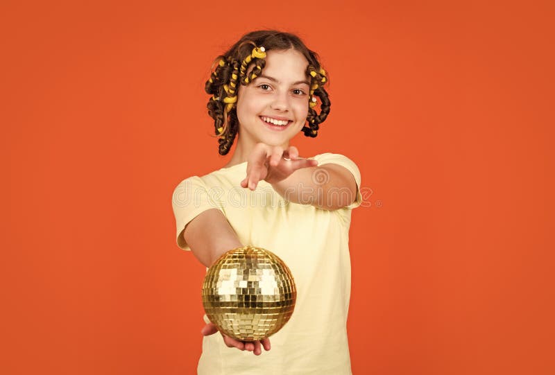 Jocoso. niña alegre con bola de disco. un chico de moda posando con rizos en el pelo. discoteca. peluquería. peinado para una fiesta disco. divertirse. fiesta retro. niño sostiene bola de disco dorada.