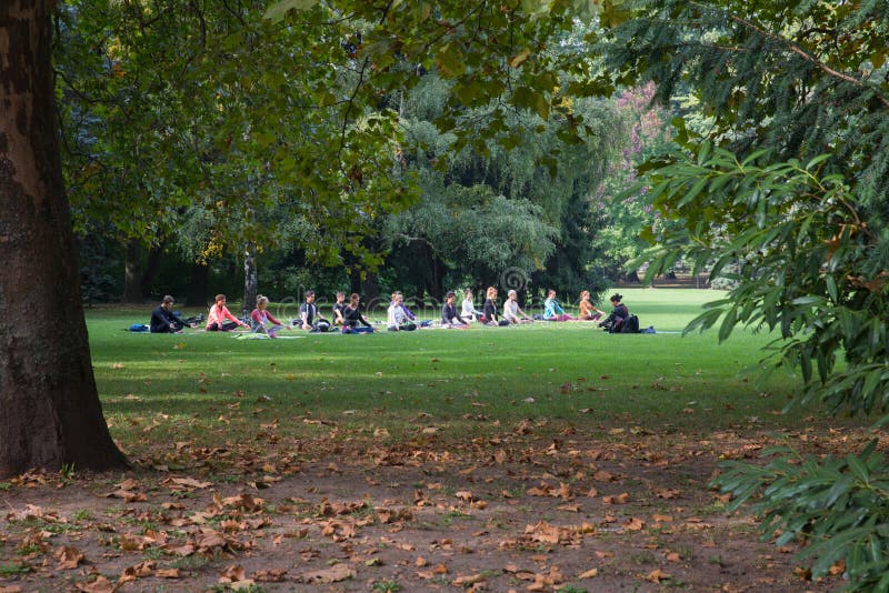 Budapest, Hungary - October 2 2016. Park Margit. Yoga in the park Margaret, Budapest, Hungary. A group of young people under the guidance of an Asian woman doing yoga. Budapest, Hungary - October 2 2016. Park Margit. Yoga in the park Margaret, Budapest, Hungary. A group of young people under the guidance of an Asian woman doing yoga.