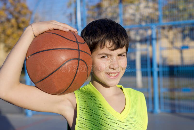 Jogador de basquetebol novo que está na corte que veste um s amarelo imagens de stock Jogador de basquetebol novo que está na corte que veste um s amarelo imagens de stock