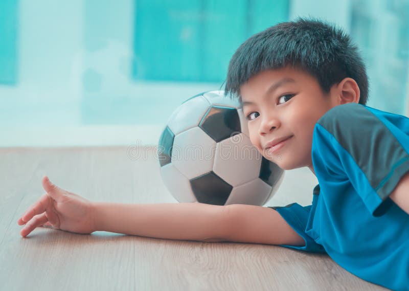 Menino Do Jogador De Futebol Que Pisa Na Bola Na Sala Imagem de